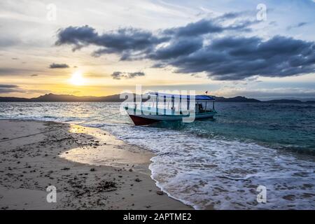 Bateau sur la plage au coucher du soleil, Pulau Kelelawar (île de Bat) ; Papouasie occidentale, Indonésie Banque D'Images