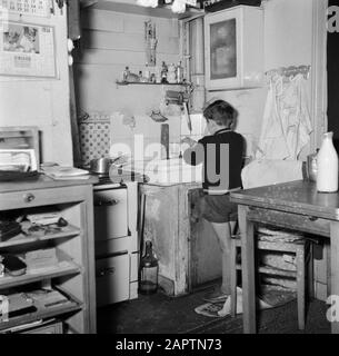 Le travail quotidien d'un concierge dans un immeuble d'appartements à Paris Le petit garçon du concierge se lave les mains dans la cuisine Date: 1954 lieu: France, Paris mots clés: Mains, cuisines, enfants, lavage Banque D'Images