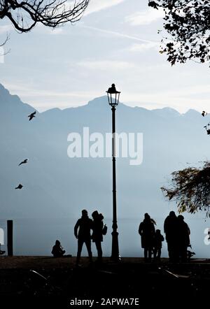 Silhouette de personnes marchant sur les rives du lac de Garde dans le nord de l'Italie Banque D'Images