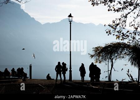 Silhouette de personnes marchant sur les rives du lac de Garde dans le nord de l'Italie Banque D'Images