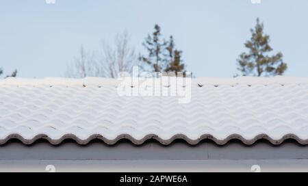 toit couvert de neige d'une maison et ciel bleu et arbres Banque D'Images