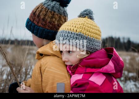 fille câliner son frère tout en jouant dans la neige dehors Banque D'Images