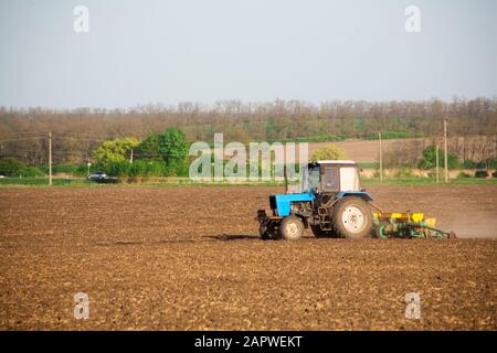 L'agriculteur sur le tracteur avec le semoir mécanique joint sème les graines sur le terrain Banque D'Images