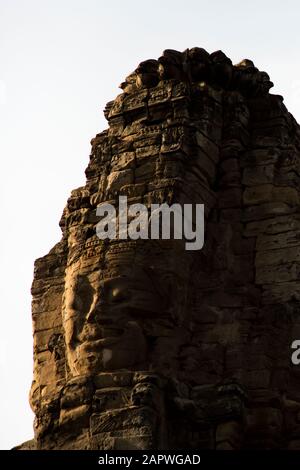 Face sculptée sur la tour du temple Bayon au coucher du soleil, Angkor, Siem Reap Banque D'Images