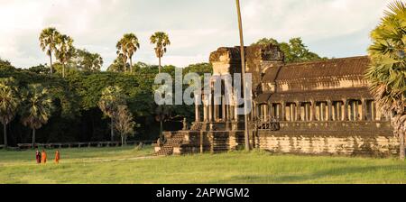 Trois moines bouddhistes marchant autour d'Angkor Wat pendant un coucher de soleil Banque D'Images