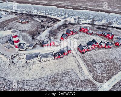 Maisons rouges en bois du village de pêcheurs dans la neige couverte en hiver. Village de pêcheurs moderne et élégant avec vue sur les yeux des oiseaux. Quelques maisons rouges près de l' Banque D'Images