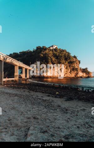 Plage entourée par la mer et rochers couverts de verdure Avec un pont au Brésil Banque D'Images