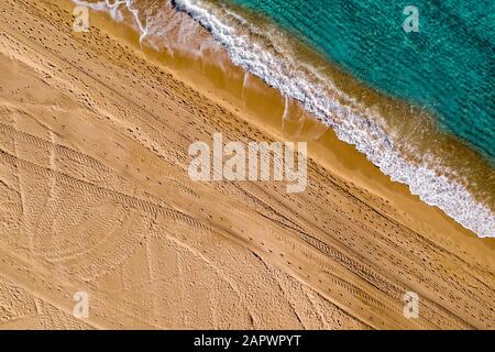 Vue aérienne des marques de pas et des voies du véhicule dans le sable sur la plage d'Alicante Espagne avec de l'eau turquoise Banque D'Images