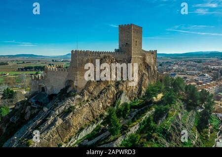 Vue aérienne du château médiéval d'Almansa avec donjon et cour sur un rocher émergeant du plateau entouré d'un anneau circulaire de maisons de toit rouge Banque D'Images