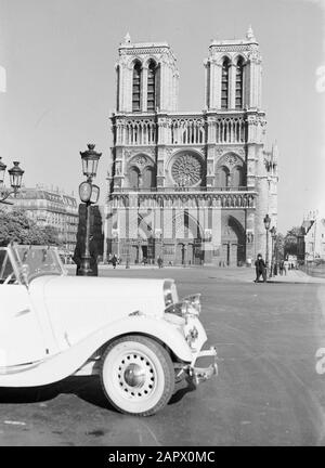 Reportage Paris Paris. Façade ouest de la cathédrale notre Dame avec une voiture de tourisme et des lampes de rue au premier plan Date: 1937 lieu: France, Paris mots clés: Architecture, voitures, gothique, cathédrales, tours d'église, sculptures de rue, meubles de rue, éclairage de rue Banque D'Images