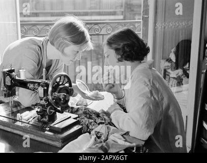 Midinettes [Hans en Renée] Renée (à gauche) et Hans derrière une machine à coudre. Hans marque ses lèvres Annotation: Hans et Renée sont les stepfilles de Van de Poll Date: 1937 lieu: France, Paris mots clés: Coupeurs, machines à coudre Nom personnel: Hans, Renée Banque D'Images