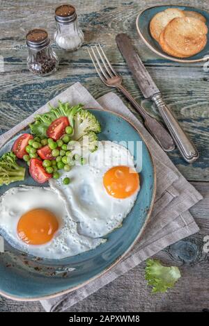 Le petit-déjeuner se compose d''œufs frits, de légumes frais et de toasts sur l''ancienne table en bois Banque D'Images