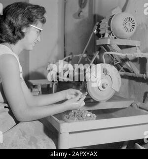 Israël - Eilat Woman travaillant sur le broyage de la pierre d'Eilat dans une entreprise où cette pierre est traitée et transformée. Date : 1 janvier 1963 lieu : Eilat, Israël mots clés : travailleurs, pierres précieuses, outils, pierres semi-précieuses, industrie, machines, meuleuses Banque D'Images