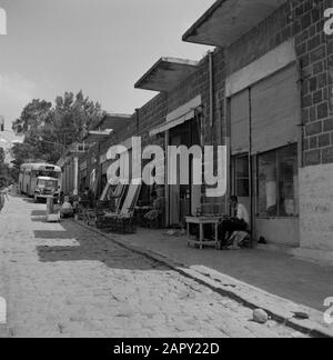 Boutiques et ateliers dans une rue de Tiberias avec un bus stationné. Les cages négociées comprennent les cages pour la volaille et les portes Date: Non daté lieu: Israël, Tiberias mots clés: Artisanat, portes, commerce, sculptures de rue, magasins Banque D'Images