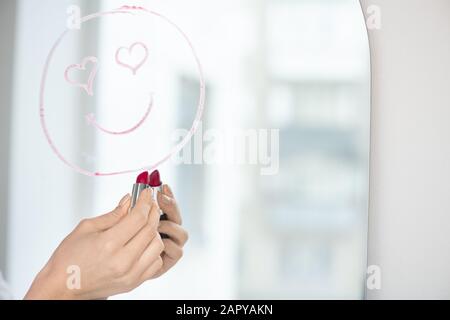 Main de jeune femme amore dessiner visage avec le sourire et les yeux en forme de coeur Banque D'Images