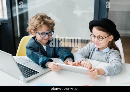 Joyeux écolier qui pointe sur l'écran tactile pendant la présentation Banque D'Images