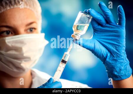 Un médecin en gants médicaux portant une bouteille avec un vaccin et une seringue avant d'effectuer l'injection. Gros plan. Concept de médecine et de santé Banque D'Images