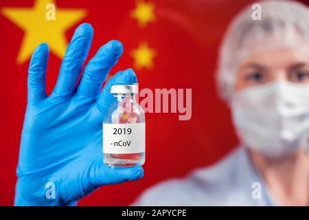 Médecin en gants médicaux bleus portant une bouteille avec vaccin devant le drapeau de la Chine. Gros plan. Coronavirus, épidémie et concept de santé Banque D'Images