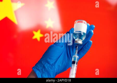 Médecin en gants médicaux bleus contenant une bouteille avec vaccin et seringue devant le drapeau de la Chine. Gros plan. Coronavirus, épidémie et santé Banque D'Images