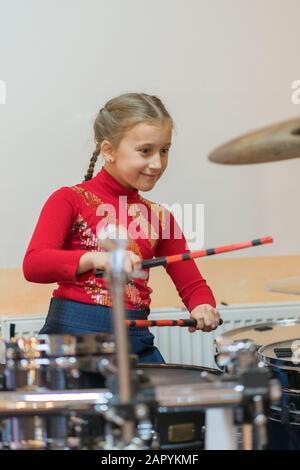 Fille de l'adolescence à jouer de la batterie. Les adolescentes ont de l'amusement jouer ensembles de batterie en cours de musique. photo verticale. Banque D'Images