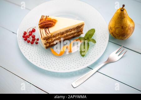 Morceau de gâteau de carottes avec crème de lait, carottes et noix isolées, closure Banque D'Images