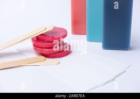 Cire rouge pour l'épilation en comprimés et cassettes, bâtonnets en bois et bandes sur fond blanc Banque D'Images