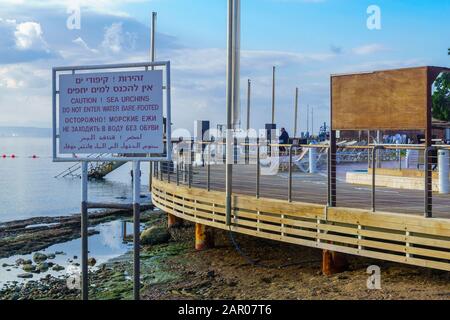 Eilat, Israël - 19 janvier 2020: Vue sur la côte, et promenade, avec visiteurs et panneau d'avertissement. Eilat est la ville la plus au sud d'Israël Banque D'Images