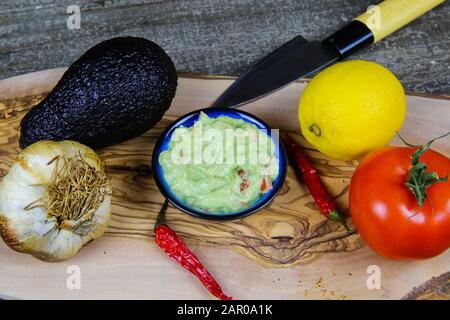 Ingrédients pour la sauce guacamole : avocat, agrumes, tomate, ail, chilis, couteau sur table en bois Banque D'Images