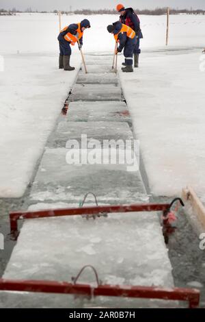 Les employés radeau des blocs de glace le long d'une chaîne coupée un lac gelé Banque D'Images