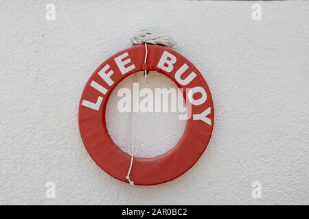 Bouée de vie rouge sur mur de briques en béton blanc, Ile Maurice. Banque D'Images