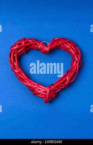 Wicker cœur rouge sur fond bleu. Carte de souhaits pour une Saint-Valentin. L'espace de copie, mise à plat, vue du dessus. Banque D'Images