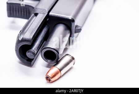 Un noir 9 mm semi-automatique avec sa lame ouverte montrant le fourreau avec une puce creuse de 9 mm à côté sur un fond blanc Banque D'Images