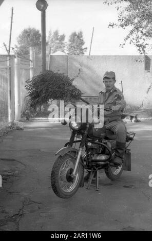 STUPINO, RÉGION DE MOSCOU, RUSSIE - VERS 1993: Portrait d'un officier de l'armée russe sur une moto et un balai dans sa main. Noir et blanc. Numérisation de film. Gros grain. Banque D'Images