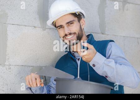 le travailleur de la construction plâtrant le mur à l'aide de plâtre de ciment Banque D'Images