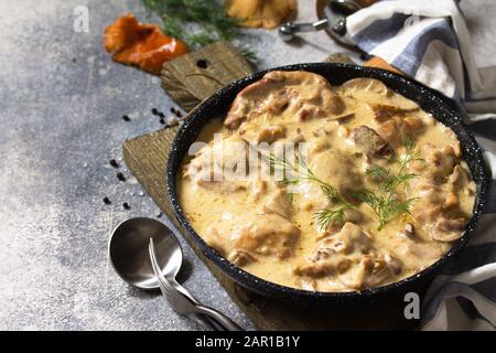 Fricasse - Cuisine Française. Poulet cuit dans une sauce crémeuse aux champignons dans une poêle sur fond de pierre légère.