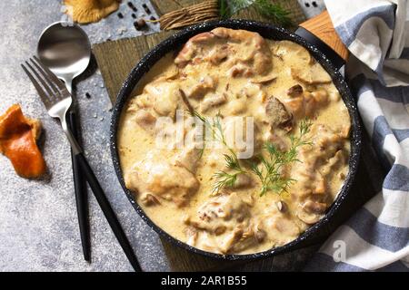 Fricasse - Cuisine Française. Poulet cuit dans une sauce crémeuse aux champignons dans une poêle sur fond de pierre légère.
