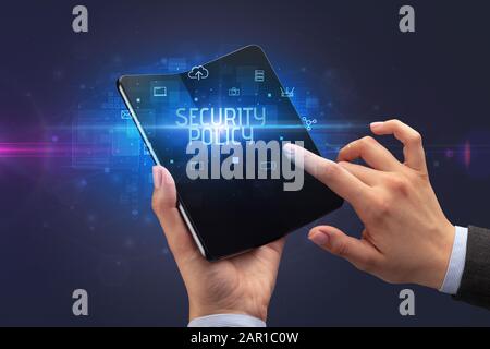 Homme d'affaires tenant un smartphone pliable avec inscription À LA POLITIQUE DE SÉCURITÉ, concept de cyber-sécurité