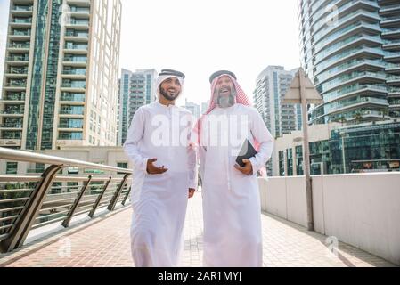 Deux hommes d'affaires avec emirates traditionnelle réunion de vêtements à Dubaï - Senior et jeunes adultes ayant des affaires aux Emirats Arabes Unis Banque D'Images