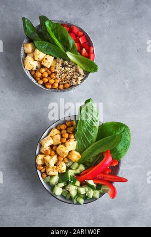 Salade De Tofu Frite Avec Concombres, Pois Chiches Frits, Feuilles De Légumes Et Graines De Sésame. Salade végétalienne équilibrée colorée pour un déjeuner sain dans des bols en céramique Banque D'Images