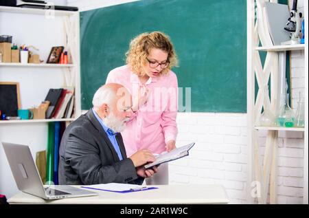 Résolution des tâches mathématiques. Concept d'éducation scolaire. Vérifier les devoirs. Éducateur et étudiant regardant le livre. Expliquer un sujet difficile. L'étudiant est perplexe par quelques informations. Un étudiant demande à l'enseignant la tâche. Banque D'Images