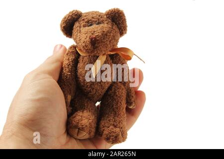 Personne tenant un petit ours en peluche dans la paume de sa main sur fond blanc Banque D'Images