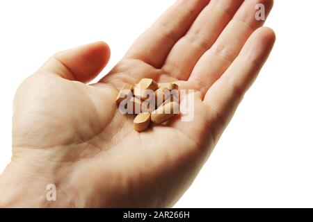 Gros plan d'une personne tenant un tas de pilules sur fond blanc Banque D'Images