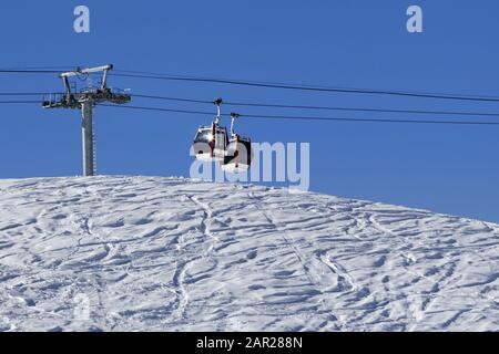 Télécabine, piste de ski hors piste avec trace de skis et de snowboards. Haute montagne d'hiver et ciel bleu clair en journée ensoleillée. Banque D'Images