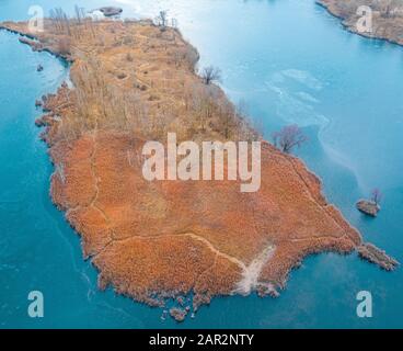 Petite île avec arbres sans feuilles et végétation orange sèche, au centre du lac Hammers, vue sur les drones. Banque D'Images