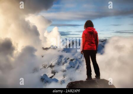 Une fille aventureuse qui regarde le Magnifique coucher De soleil Spectaculaire au sommet des montagnes. Image composite avec paysage prise en Colombie-Britannique, Canada. Con Banque D'Images