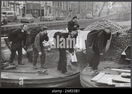 Pénurie de charbon au début de l'hiver. Les barges de charbon sont recouvertes d'une couche de mûres le matin, mais les travailleurs du charbon continuent de remplir les sacs et de retirer les sacs de charbon abaissés Date: 13 décembre 1955 lieu: Amsterdam, Noord-Holland mots clés: Population, charbon, hivers Banque D'Images