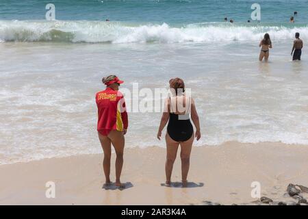 Un sauveteur féminin d'Australie sur la plage qui prend à une autre dame, Byron Bay, Australie Banque D'Images