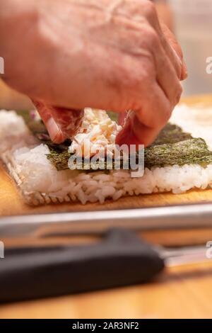 Démonstration du rouleau à sushi sur la façon de placer des ingrédients pour un rouleau à sushi extérieur, avec du riz et des algues Banque D'Images