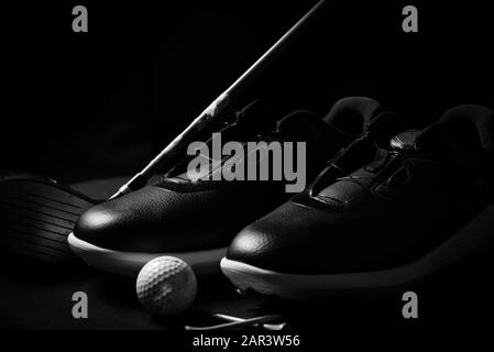 Chaussures de golf, balles, tee-shirts et club de golf isolés sur fond noir. Banque D'Images