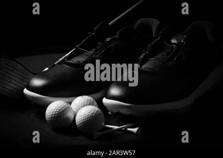 Chaussures de golf, balles, tee-shirts et club de golf isolés sur fond noir. Banque D'Images